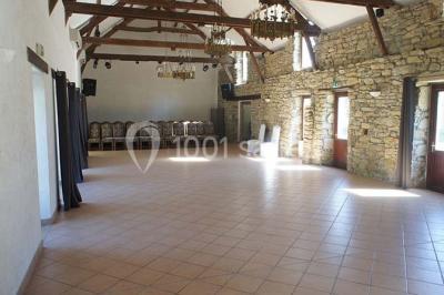 Étang calme entouré d'arbres avec un bâtiment blanc visible en arrière-plan sous un ciel bleu.