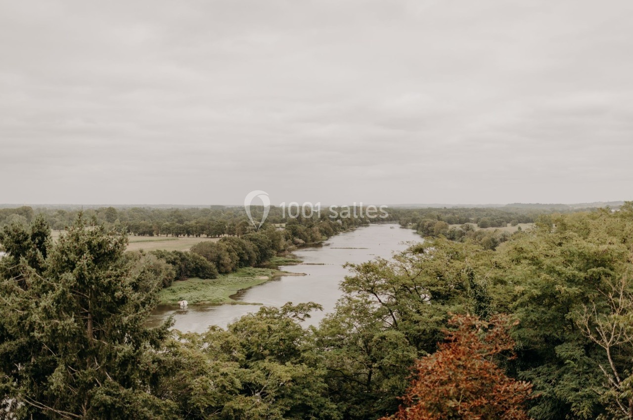 Vue d'une rivière entourée de végétation dense sous un ciel nuageux.