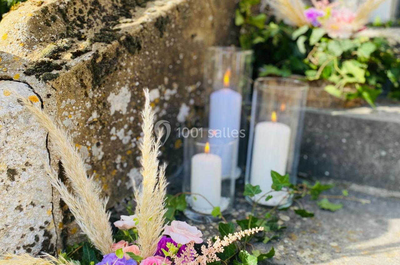 Location salle Saint-Léger-en-Bray (Oise) - Domaine du Colombier #15 Composition florale avec roses, gerberas et herbes de la pampa, disposée sur des marches en pierre avec des bougies allumées.