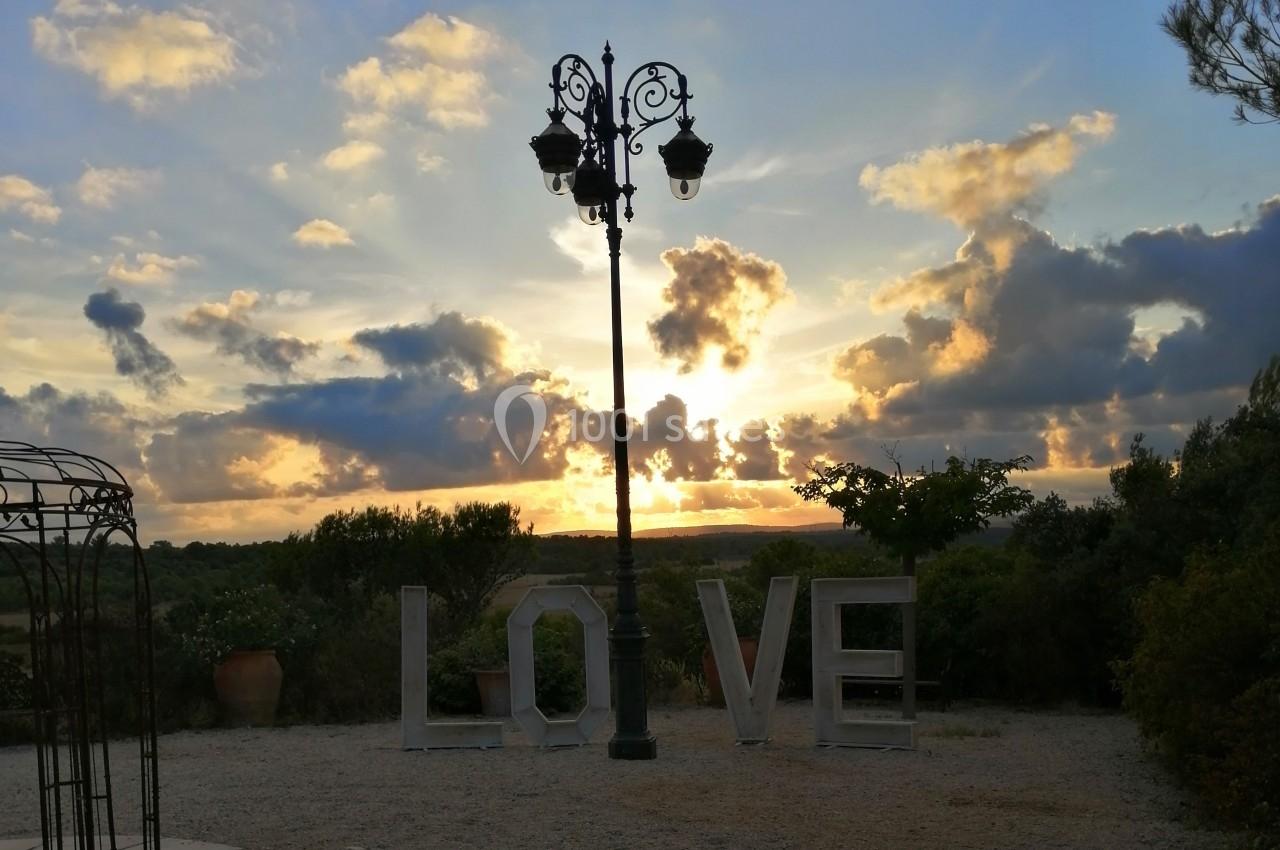 Lampadaire au centre d'un jardin au coucher du soleil, avec le mot ’LOVE’ formé par des lettres géantes.