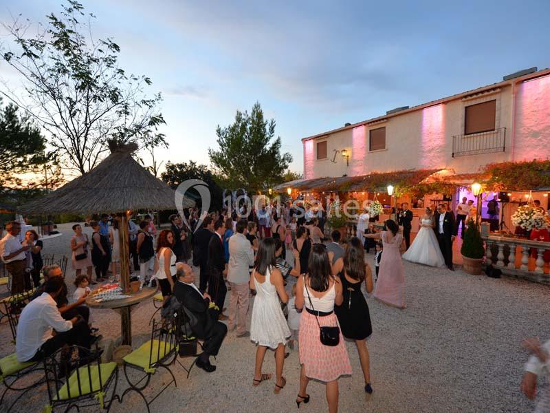 Groupe de personnes rassemblées en extérieur lors d'une réception de mariage devant un bâtiment éclairé.