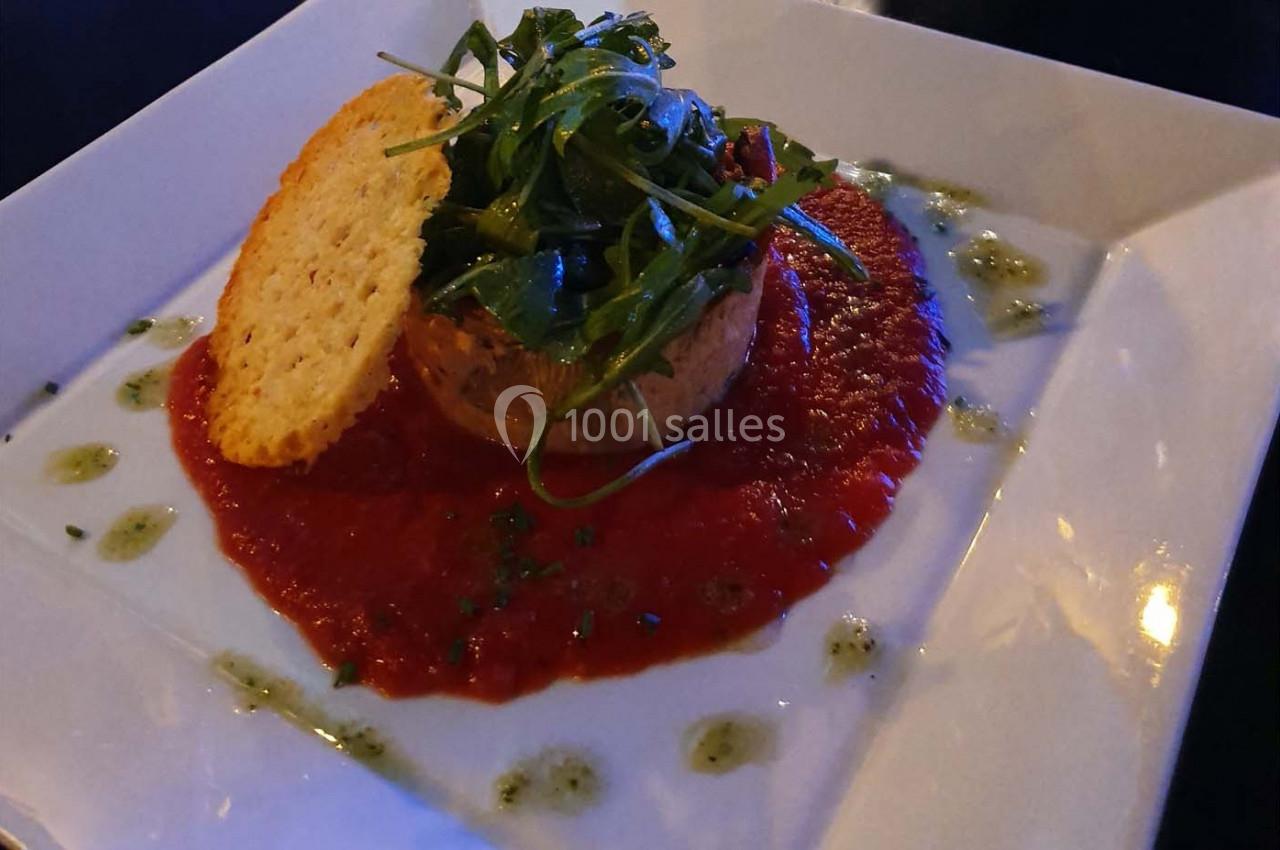 Plat raffiné composé d'une mousse sur coulis de tomate, garni de roquette et d'une tuile croustillante.