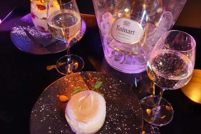 Miniature Location salle Paris 15 (Paris) - Tout Le Monde En Parle Montparnasse #18 Assiette de viande garnie de roquette et sauce rouge, servie sur une table avec des verres de vin en arrière-plan.