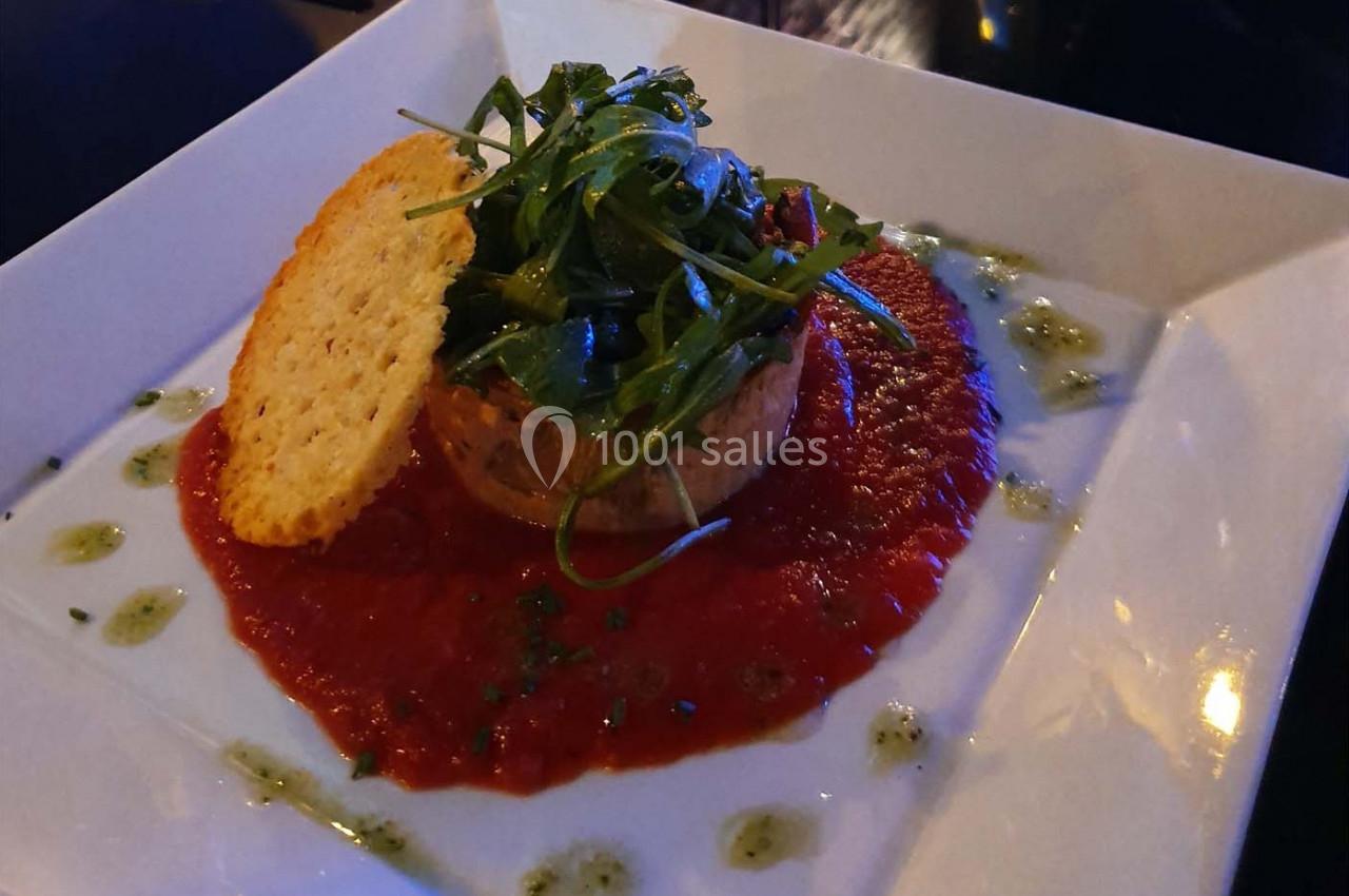 Tartare de saumon sur coulis de tomate, garni de roquette, tuile de parmesan et filet de sauce verte.