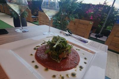 Miniature Location salle Paris 15 (Paris) - Tout Le Monde En Parle Montparnasse #22 Assiette de viande garnie de roquette et sauce rouge, servie sur une table avec des verres de vin en arrière-plan.