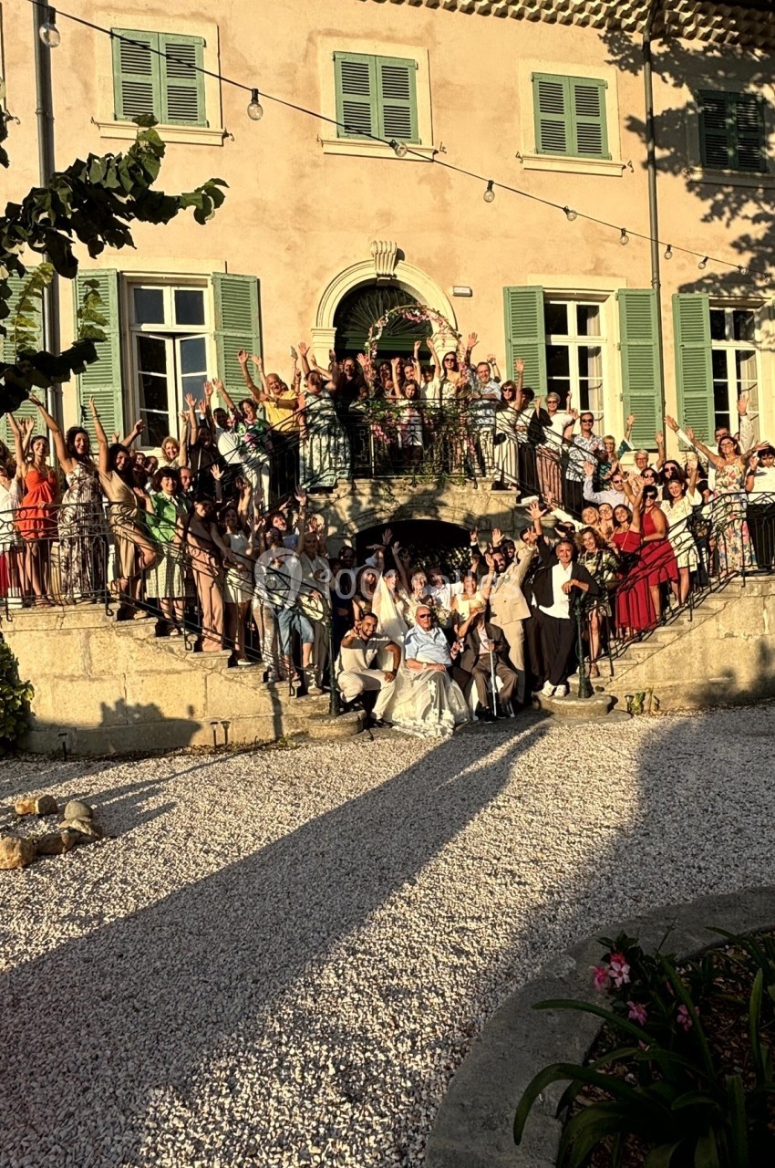 Groupe de personnes célébrant sur les marches d'un bâtiment ancien avec des volets verts, éclairé par une lumière de fin de…