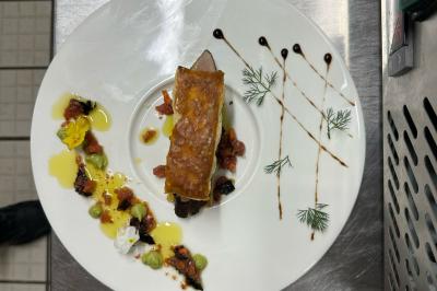 Comptoir de réception en bois avec étagères éclairées contenant des bouteilles et des verres, décoré de plantes séchées.