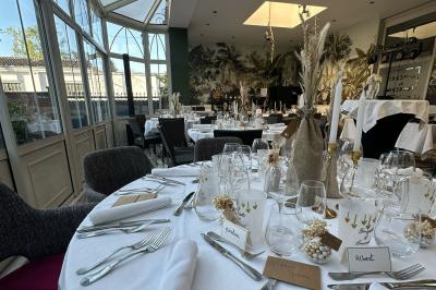 Comptoir de réception en bois avec étagères éclairées contenant des bouteilles et des verres, décoré de plantes séchées.