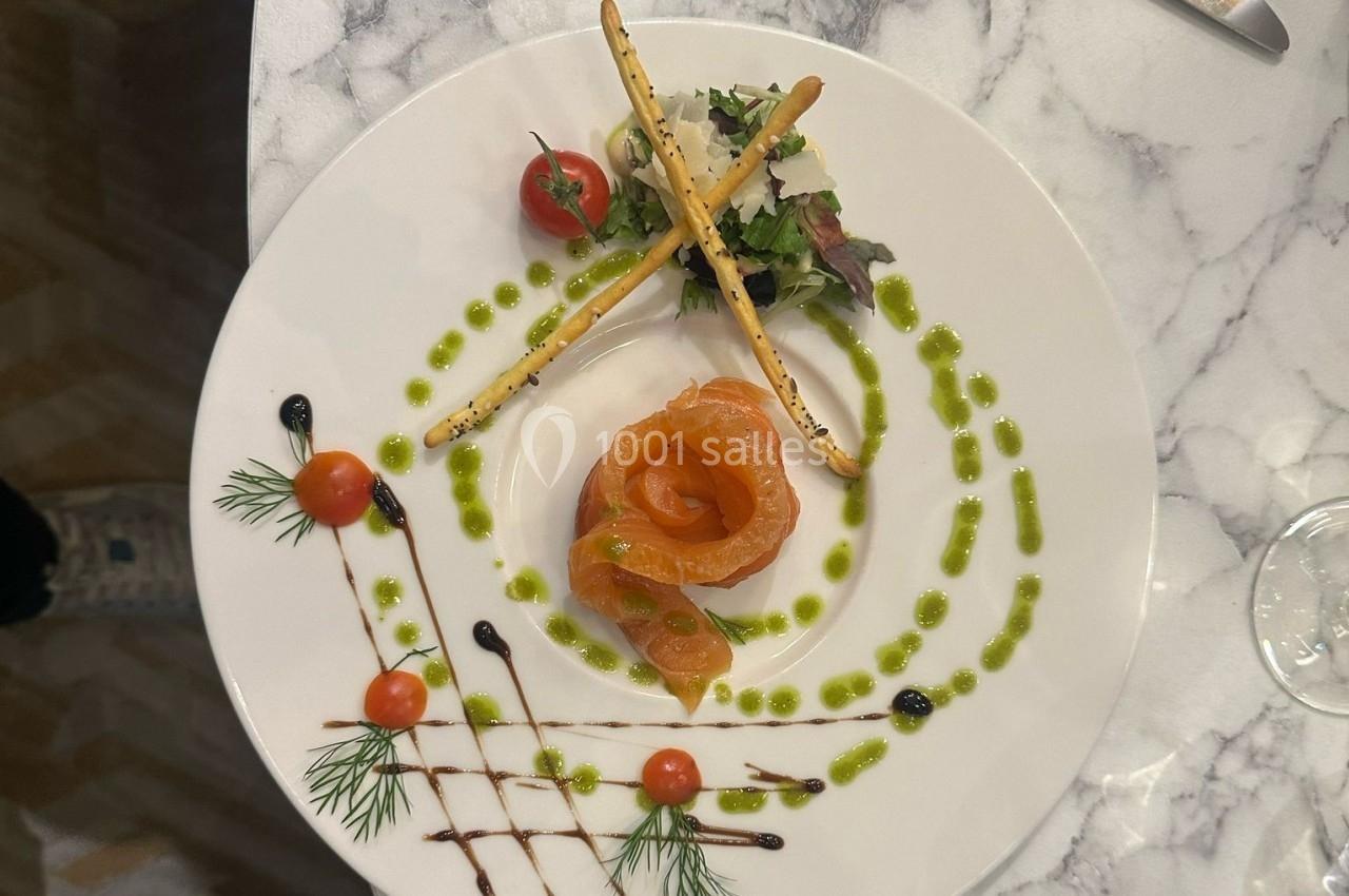Assiette gastronomique avec saumon fumé, tomates cerises, grissini, herbes fraîches et décorations de sauces colorées.