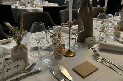 Comptoir de réception en bois avec étagères éclairées contenant des bouteilles et des verres, décoré de plantes séchées.