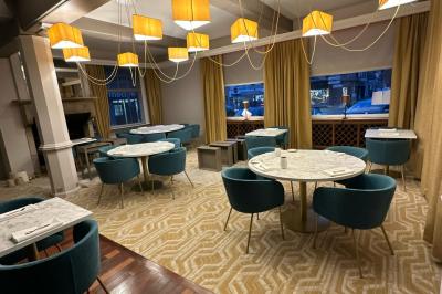 Comptoir de réception en bois avec étagères éclairées contenant des bouteilles et des verres, décoré de plantes séchées.