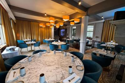 Comptoir de réception en bois avec étagères éclairées contenant des bouteilles et des verres, décoré de plantes séchées.