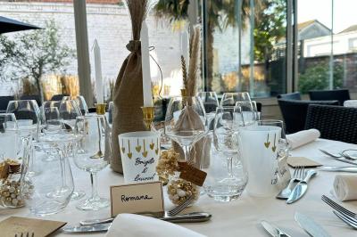 Comptoir de réception en bois avec étagères éclairées contenant des bouteilles et des verres, décoré de plantes séchées.