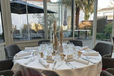 Comptoir de réception en bois avec étagères éclairées contenant des bouteilles et des verres, décoré de plantes séchées.