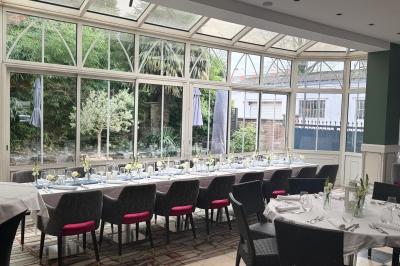 Comptoir de réception en bois avec étagères éclairées contenant des bouteilles et des verres, décoré de plantes séchées.