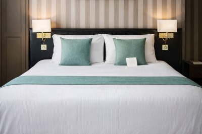 Comptoir de réception en bois avec étagères éclairées contenant des bouteilles et des verres, décoré de plantes séchées.