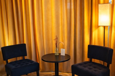 Comptoir de réception en bois avec étagères éclairées contenant des bouteilles et des verres, décoré de plantes séchées.