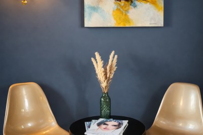 Comptoir de réception en bois avec étagères éclairées contenant des bouteilles et des verres, décoré de plantes séchées.