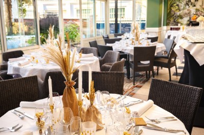 Comptoir de réception en bois avec étagères éclairées contenant des bouteilles et des verres, décoré de plantes séchées.