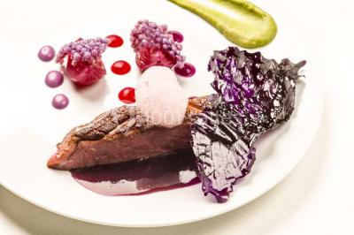 Comptoir de réception en bois avec étagères éclairées contenant des bouteilles et des verres, décoré de plantes séchées.