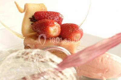 Comptoir de réception en bois avec étagères éclairées contenant des bouteilles et des verres, décoré de plantes séchées.