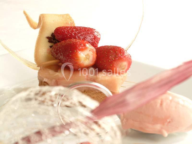 Dessert composé de fraises fraîches, d'une pâtisserie, de glace rose et de décorations en sucre.