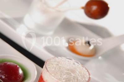 Comptoir de réception en bois avec étagères éclairées contenant des bouteilles et des verres, décoré de plantes séchées.