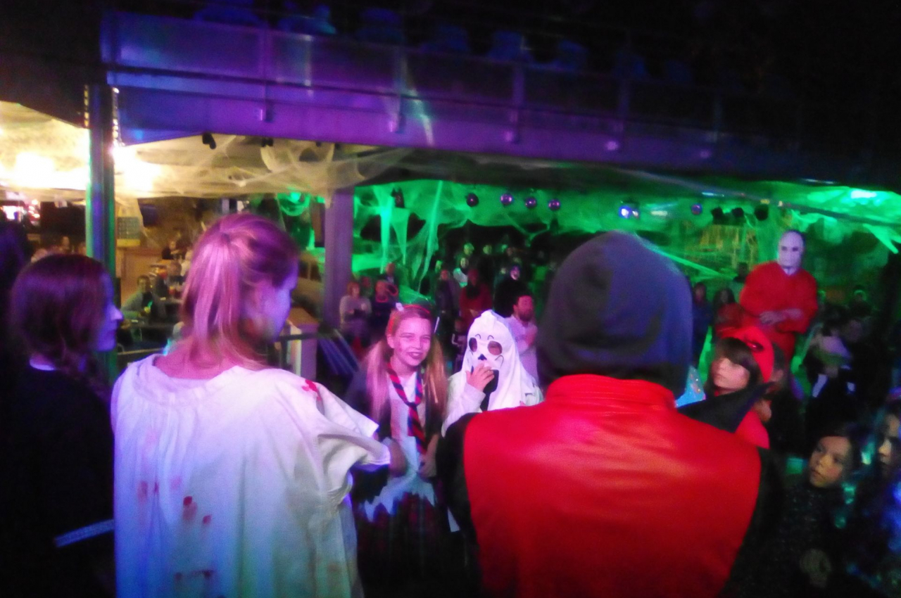 Des personnes déguisées en costumes effrayants participent à un événement festif dans un décor sombre et lumineux.