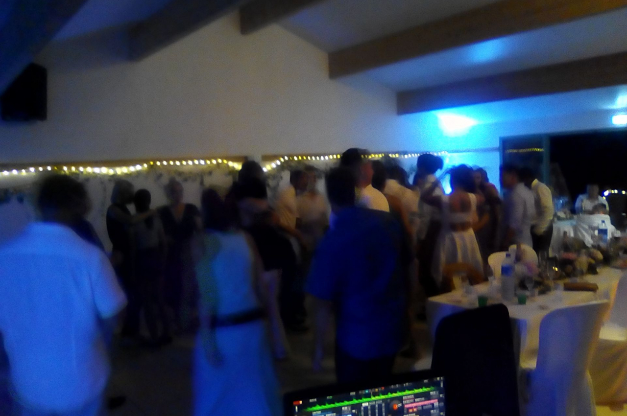 Groupe de personnes dans une salle éclairée, dansant et discutant lors d'un événement festif en soirée.