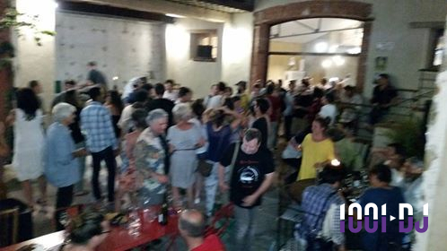 Groupe de personnes rassemblées en soirée dans une cour extérieure, discutant et partageant un moment convivial.