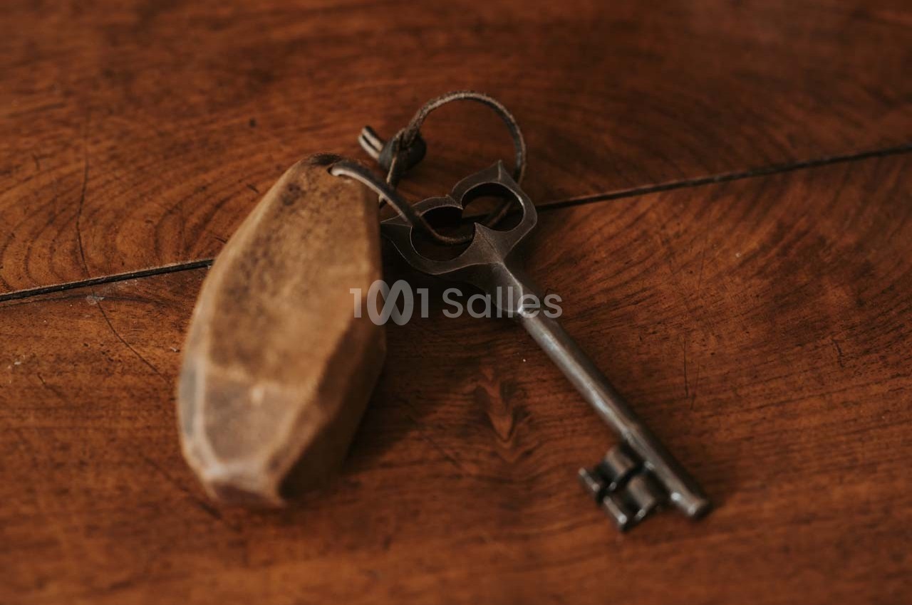 Clé ancienne en métal avec un porte-clés en bois posé sur une surface en bois.