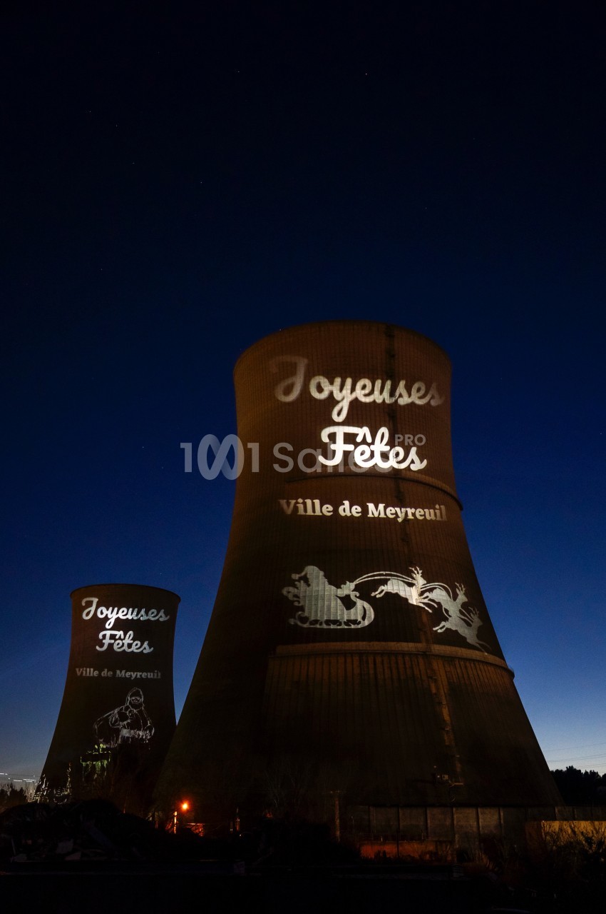 Tours de refroidissement illuminées par des projections de vœux festifs et motifs décoratifs, de nuit.