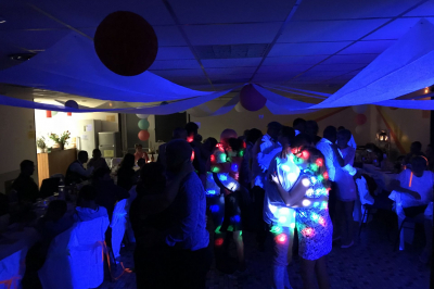 Miniature DJ Bannalec (Finistère) - Big Up Anim #10 Scène décorée avec guirlandes lumineuses, plantes et une table de DJ éclairée en bleu et blanc.