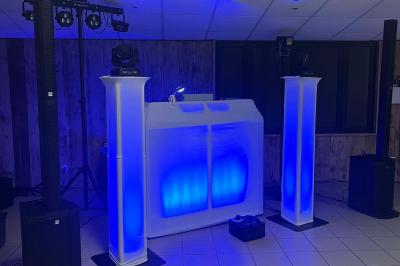 Miniature DJ Bannalec (Finistère) - Big Up Anim #13 Scène décorée avec guirlandes lumineuses, plantes et une table de DJ éclairée en bleu et blanc.