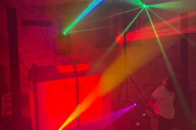 Miniature DJ Bannalec (Finistère) - Big Up Anim #14 Scène décorée avec guirlandes lumineuses, plantes et une table de DJ éclairée en bleu et blanc.