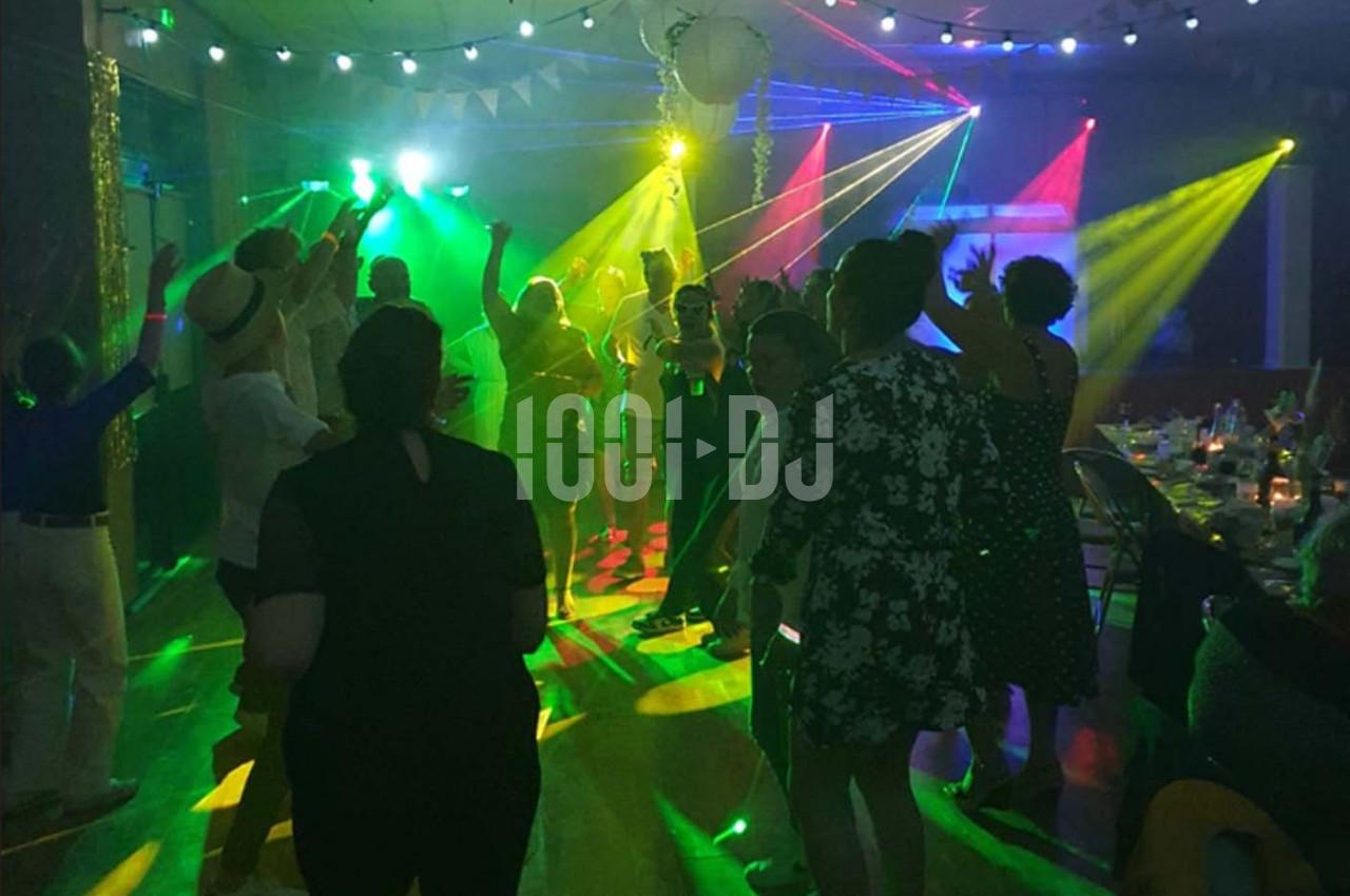 Personnes dansant sous des éclairages colorés dans une salle de fête décorée.