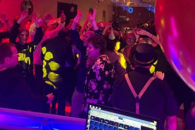 Stand de DJ avec éclairage LED rouge et vert, installé dans une salle avec décoration intérieure et lumière naturelle.