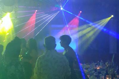 Stand de DJ avec éclairage LED rouge et vert, installé dans une salle avec décoration intérieure et lumière naturelle.