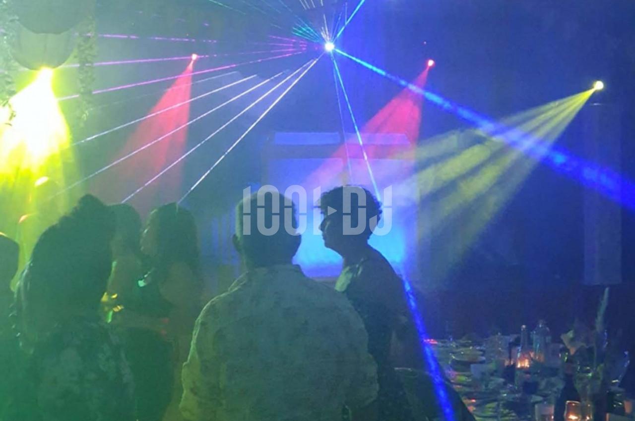 Personnes dansant sous des jeux de lumières colorées dans une ambiance festive et enfumée.