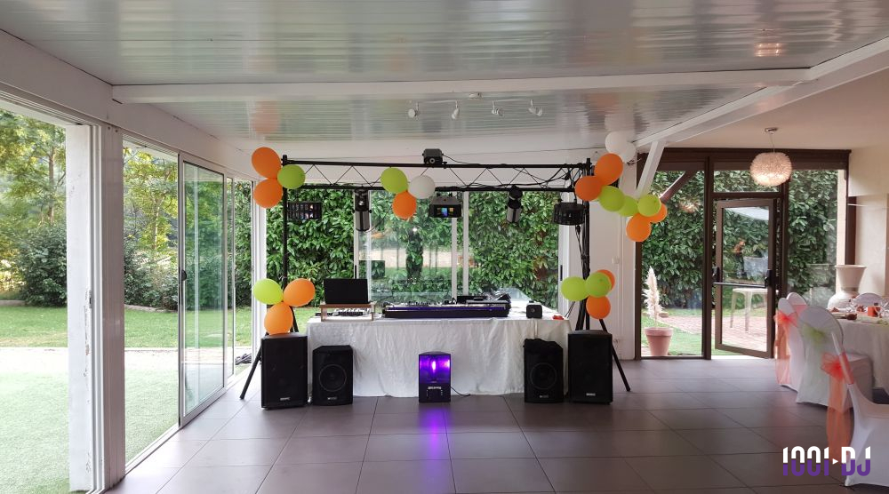 Installation de matériel de sonorisation et éclairage avec ballons colorés dans une salle lumineuse donnant sur un jardin.