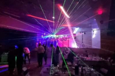Miniature DJ Diémoz (Isère) - FeeJoliEvents #4 Salle sombre avec des jeux de lumières colorées et des personnes dansant sous des faisceaux laser.