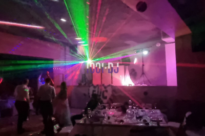 Salle sombre avec des jeux de lumières colorées et des personnes dansant sous des faisceaux laser.