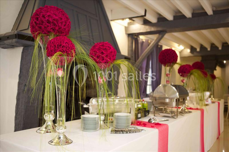 Table de buffet décorée avec des compositions florales rouges et des éléments de service en acier inoxydable.