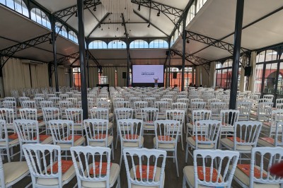 Espace lumineux avec tables hautes, affiches de mode et personnes discutant sous une structure métallique.
