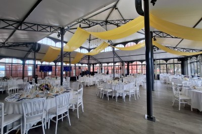 Espace lumineux avec tables hautes, affiches de mode et personnes discutant sous une structure métallique.