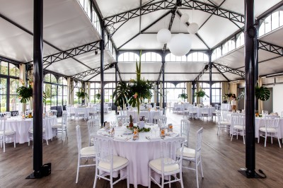 Espace lumineux avec tables hautes, affiches de mode et personnes discutant sous une structure métallique.