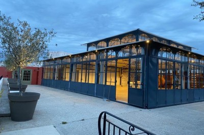 Espace lumineux avec tables hautes, affiches de mode et personnes discutant sous une structure métallique.