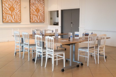 Espace lumineux avec tables hautes, affiches de mode et personnes discutant sous une structure métallique.