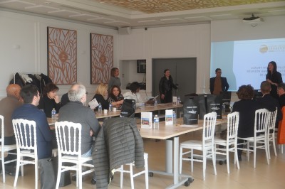 Espace lumineux avec tables hautes, affiches de mode et personnes discutant sous une structure métallique.