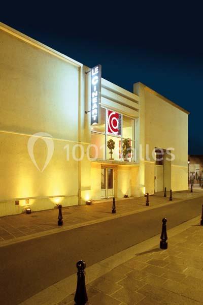 Façade éclairée d'un cinéma avec enseigne lumineuse et entrée principale visible de nuit.